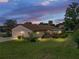 Twilight shot of home featuring an attached two car garage, screened in porch, and lush landscaping at 37821 Willingham Ave, Dade City, FL 33525