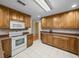 Well-lit kitchen with wood cabinets, white appliances, and tile flooring at 37821 Willingham Ave, Dade City, FL 33525