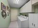 Bright laundry room offers a washer, dryer, storage cabinets, and tiled flooring at 37821 Willingham Ave, Dade City, FL 33525