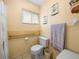 Neutral bathroom featuring grab bars, toilet, and window with decorative curtain at 37821 Willingham Ave, Dade City, FL 33525