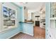 Kitchen with pastel blue walls, white cabinetry, and terra cotta-colored tiled flooring at 4435 1St S Ave, St Petersburg, FL 33711