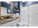 Stylish bathroom featuring blue accent wall, granite countertop, wood-framed mirror, and a shower with glass doors at 4465 Tubular Run, Land O Lakes, FL 34638