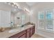 Bathroom featuring double sinks, dark wood cabinets, a large mirror, and natural light from shuttered windows at 6207 Bleeker St, Riverview, FL 33578