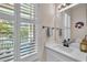 Bathroom with a single vanity, shaker-style cabinets, decorative accents, and a window with white shutters at 6207 Bleeker St, Riverview, FL 33578