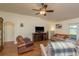 Cozy living area with wood-look floors, a ceiling fan, and a view of the lanai at 6351 Desert Peace Ave, Land O Lakes, FL 34639