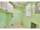 Practical laundry room with bright green walls, white cabinets, and a window for natural light at 6730 10Th Avenue S Ter, St Petersburg, FL 33707