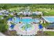 Aerial view of community pool, clubhouse, and recreational facilities with palm trees and lounge chairs at 8332 Swiss Chard Cir, Land O Lakes, FL 34637