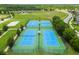 Aerial view of community tennis and basketball courts with green and blue surfaces surrounded by green trees at 8332 Swiss Chard Cir, Land O Lakes, FL 34637