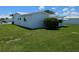 Lush green backyard with exterior of the house, showing white roof and walls at 9218 40Th N Way, Pinellas Park, FL 33782