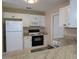 Bright kitchen featuring granite counters, white appliances, and ample cabinet space at 9218 40Th N Way, Pinellas Park, FL 33782