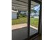 View through glass patio doors to the green lawn and multiple residences in the backyard at 9218 40Th N Way, Pinellas Park, FL 33782