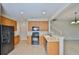 Kitchen featuring wood cabinets, black appliances, and tiled flooring next to stairs at 10132 Post Harvest Dr, Riverview, FL 33578