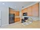 Eat-in kitchen showcasing wooden cabinets, black appliances, and durable tile flooring at 10132 Post Harvest Dr, Riverview, FL 33578