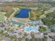 An expansive aerial view of a golf community, including clubhouse, pool, tennis courts, and a scenic lake at 10559 Coral Key Ave, Tampa, FL 33647