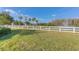 View of the pond surrounded by green grass, palm trees and a white fence at 10559 Coral Key Ave, Tampa, FL 33647