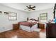 Bedroom with hardwood floors, a ceiling fan, two windows, and a bed with dark wood frame at 11317 Fort King Rd, Dade City, FL 33525