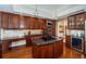 Gourmet kitchen with stainless steel appliances, granite countertops, custom cabinets, and central island cooktop at 1303 Forestedge Blvd, Oldsmar, FL 34677