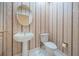 Charming powder room with pedestal sink, oval mirror, and classic striped wallpaper at 1303 Forestedge Blvd, Oldsmar, FL 34677