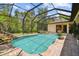 Beautiful screened-in pool and spa with rock waterfall feature, surrounded by lush landscaping at 13503 Gopher Pond Ct, Hudson, FL 34669