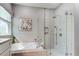 Bright bathroom featuring a glass-enclosed shower with tiled walls, a soaking tub, and stylish fixtures at 14427 Pepperpine Dr, Tampa, FL 33626