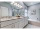 Elegant bathroom featuring a double vanity with granite countertops and a separate soaking tub at 14427 Pepperpine Dr, Tampa, FL 33626