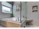 Bright bathroom featuring a glass-enclosed shower with tiled walls and a soaking tub at 14427 Pepperpine Dr, Tampa, FL 33626