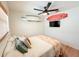 Comfortable bedroom with ceiling fan, surfboard wall decor, and wood-look flooring at 1972 Briarwood St, Dunedin, FL 34698