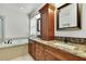 Bright bathroom featuring dual sinks with granite counters and separate soaking tub at 22431 Panther Run Ct, Land O Lakes, FL 34639