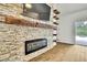 Close-up view of a stone fireplace with wood accents, a modern electric firebox, and a mounted TV at 22431 Panther Run Ct, Land O Lakes, FL 34639