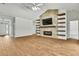 Open living room with a fireplace, floating shelves, wood-look tile flooring, and a ceiling fan at 22431 Panther Run Ct, Land O Lakes, FL 34639