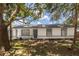 Home's facade showcasing stucco siding, gray trim, gray front door, mature trees, and a well-manicured lawn at 22716 Penny Loop, Land O Lakes, FL 34639