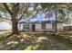 Charming home featuring stucco siding, gray trim, gray front door, mature trees, and a well-manicured lawn at 22716 Penny Loop, Land O Lakes, FL 34639