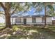 Charming home featuring stucco siding, gray trim, gray front door, mature trees, and a well-manicured lawn at 22716 Penny Loop, Land O Lakes, FL 34639