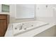 Relaxing soaking tub with chrome faucet and white tile surround complemented by bright window at 2544 Rosehaven Dr, Wesley Chapel, FL 33544