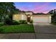 Inviting single-story home featuring a two-car garage and well-maintained landscaping under a colorful dusk sky at 2544 Rosehaven Dr, Wesley Chapel, FL 33544