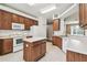 Well-lit kitchen featuring wood cabinets, white appliances, and a kitchen island at 2544 Rosehaven Dr, Wesley Chapel, FL 33544
