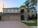 Two-story home with a three-car garage, brick driveway, and manicured landscaping at 29916 Cedar Waxwing Dr, Wesley Chapel, FL 33545