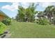 Expansive backyard featuring lush green grass and mature trees with a fire pit and chair at 3156 Depew Ave, Port Charlotte, FL 33952