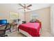A functional bedroom featuring a ceiling fan, a desk, two windows, tile flooring, and a comfortable bed at 3156 Depew Ave, Port Charlotte, FL 33952