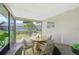 A sunroom with a view of the pool. Contains tile flooring and four wicker chairs around a round table at 3156 Depew Ave, Port Charlotte, FL 33952