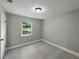 Bedroom featuring light gray walls, wood-look tile floors, and a window providing natural light and outdoor views at 34819 Hibiscus Dr, Dade City, FL 33523
