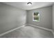 This bedroom offers light gray walls, wood-look tile flooring, and a window providing backyard views at 34819 Hibiscus Dr, Dade City, FL 33523