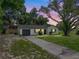 Charming home featuring a well-maintained lawn, a painted brick exterior, attached garage, and mature trees at 34819 Hibiscus Dr, Dade City, FL 33523