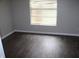 Comfortable bedroom with neutral walls, dark wood-look floors and a large window at 38668 Ferm Cir, Zephyrhills, FL 33540