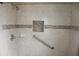 Close up of an accessible tile shower with grab bar, built-in niche, and chrome fixtures at 38668 Ferm Cir, Zephyrhills, FL 33540