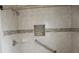 Close up of an accessible tile shower with grab bar, built-in niche, and chrome fixtures at 38668 Ferm Cir, Zephyrhills, FL 33540