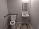 Well-lit bathroom featuring a toilet with grab bars and a white sink with a mirror at 4802 Drift Tide Dr, New Port Richey, FL 34652