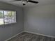 A bright bedroom featuring wood-look flooring, a ceiling fan, and a window for natural light at 4802 Drift Tide Dr, New Port Richey, FL 34652