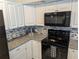 Modern kitchen features white cabinetry, black appliances, and gray countertops at 4802 Drift Tide Dr, New Port Richey, FL 34652