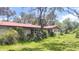 Charming single-story home with red roof, white brick, lush landscaping, and mature trees at 5540 Cyril Dr, Dade City, FL 33523